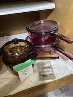 Image showing the amber covered casserole dish, cranberry saucepans with lids, and care instructions.