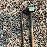 The metal crowbar and sledgehammer with wooden handle laid on gravel surface, showing full length and condition of both tools.