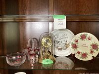 Wide shot showing entire collection including anniversary plates, glassware, and gold-tone anniversary clock under glass dome.