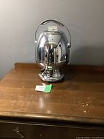 Full front view of chrome egg-shaped Philips electric coffee percolator on wooden surface.