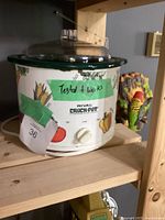 Front angled photo of Rival 3120 Crock-Pot slow cooker showing vegetable pattern, control knob, and clear glass lid with handle.