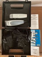 Full view of Wahl hair clipper and trimmer set with case showing two clippers, multiple comb guides, charger cord, blade oil, cleaning brush, and instruction manuals.