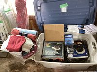 Two bins containing boxed WEN Orbital Car Waxer Model 10 and Performance Tool Polisher Buffer, cleaning cloths, and towels.