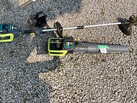 String trimmer and leaf blower laid out on gravel