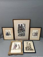 Five framed lithographs displayed on a neutral surface showing fashion and cathedral scenes.