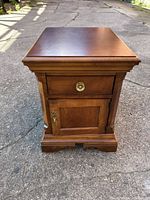 Front view of Broyhill wooden end table showing drawer and cabinet door with brass hardware.