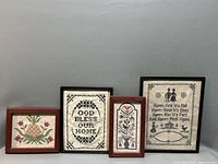 Four framed vintage needlepoint arts arranged against grey background showing variety of designs and frames.