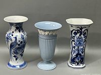 Three tall vases side by side on a gray surface, showing the full height and shapes