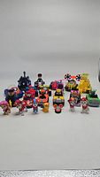 23 Paw Patrol themed toy vehicles and figures arranged in rows with characters in the front and vehicles behind, showing variety in size and color.