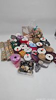 Craft lot containing assorted ribbons, buttons, and a bag of beads arranged on a white surface