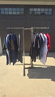 Full view of the 12 graphic tee shirts hanging on metal rack outdoors showing various colors and styles