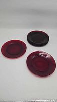 Seven red glass plates stacked and displayed separately showing round shape and red coloration