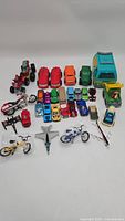 Overview of various toy vehicles including cars, trucks, motorcycles, bicycles, a helicopter, and an airplane all displayed on a white background.