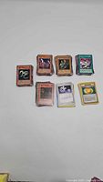 Photo showing multiple stacks of Yu-Gi-Oh! cards including monsters and spell cards on a white background
