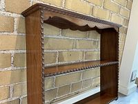 Side angled view of wooden wall shelf showing rope trim and shelves