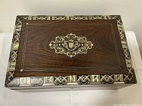 Top-down view of closed box showing overall shape, rosewood grain, and inlaid medallion