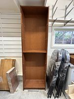 Front view of tall IKEA Billy bookshelf with two fixed shelves and shelf holes visible inside. Wrapped shelves next to unit.