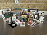 Photo showing a variety of assorted picture frames, Christmas candles, vintage floral bells, bird bell, glass bird figurines, Dolly Parton Christmas CD in packaging, decorative plates, and assorted ornaments.