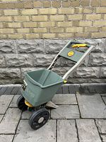 Front angled view of the green Ames fertilizer spreader showing the hopper, wheels and handle.
