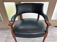 Front view of dark green leather armchair showing wood frame, leather seat, and brass studs.