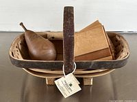 Handcrafted wooden basket holding carved wooden pear and stacked coasters with label tag