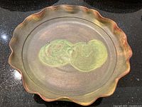 Top-down view showing full wavy-edged rim and central apple motif