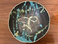 Top view of the bowl showing abstract turquoise and yellow patterns on black background.