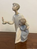 Side view showing the stature and posture of the children, candle held high, clear view of older child's face and younger child's embrace.