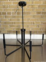 View of the chandelier standing upright showing six arms spreading out horizontally from central stem, with sockets for bulbs at the end of each arm.