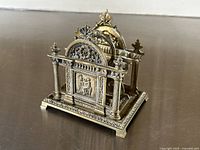 Front angled view of an ornate antique brass letter holder showing detailed relief and twisted columns.