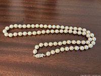 Full view of the entire pearl necklace laid out on a wooden surface