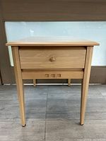 Front view showing single drawer and tapered legs