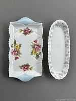 Top view of Shelley Begonia dessert tray and Wedgwood April Flowers dish side by side on grey background to show size and design