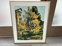 Full view of framed watercolour painting depicting a garden scene with yellow tree, table and chair, and building in the background.
