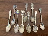 Top view showing all 9 souvenir spoons with varying designs and decorations.
