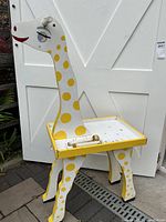 Front view of the giraffe-shaped child’s table showing shape, painted yellow spots, and flat table surface.