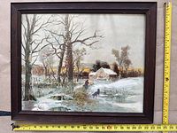 Framed artwork depicting countryside house in snow with fence and animals, measuring approximately 23 inches wide and 20 inches tall.