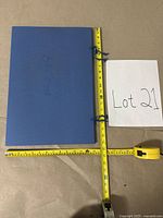 Blue folder closed next to measuring tapes showing dimensions about 11x15 inches