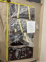 Four Asian style carved wooden panels wrapped in plastic, showing detailed scenes of agriculture and fishing life with measuring tape around for scale.