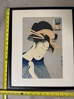 Framed artwork showing the Japanese woman in blue kimono with hair pins, measuring approximately 16.5 by 12.5 inches.