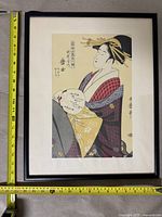 Front view of framed Japanese artwork showing female figure in kimono with fan, including measuring tape for size reference.