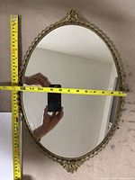 Full view of the oval mirror tray laid flat showing the measuring tape for height.