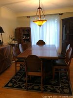 Overall view of dining room set showing rectangular table with leaf in place, six chairs, buffet on left and hutch on right under overhead fixture.