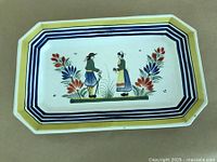 Full view of the cut-corner rectangular platter showing the hand painted border stripes and central decoration of man and woman in Breton costume with floral elements
