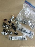 Various metal, ceramic, and glass drawer knobs and pulls on brown surface, some bagged individually