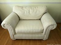 Front view of the wide armchair showing rolled arms, striped fabric upholstery, and loose back cushion.