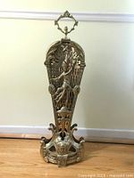 Front view of the folded brass fireplace screen featuring a figural design of a dancer and ornate cutout patterns.