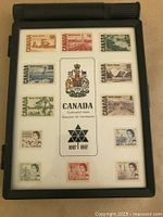 Front view of the stamp collection inside a black stamp holder showing 14 Canadian Centennial stamps from 1867-1967.