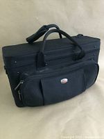 Full view of the black nylon coronet case showing handles and front storage pocket with brand logo plate.