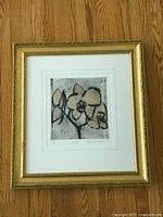 Full view of framed orchid etching artwork on wooden floor showing gilt frame and white mat.